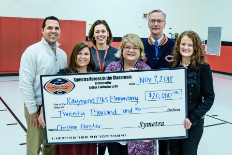 Symetra presented Ellis Elementary School with a Symetra Heroes in the Classroom “MVP Award.” The $20,000 grant will fund a bilingual after-school literacy program. Chicago Bears Chairman George McCaskey (right) joined Symetra Community Relations Assistant Director Tracy Wort (right) for the Nov. 7 presentation at the Round Lake Beach, IL, school. (Photo: Business Wire)