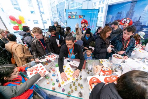 In this photo provided by Nintendo of America, Nintendo fans gather at the Nintendo NY store in Rockefeller Plaza to celebrate Mario Day (MAR10) by personalizing their Nintendo Switch systems with various Mushroom Kingdom-themed decals by Controller Gear and a special MAR10 Day-themed skin. (Photo: Business Wire)