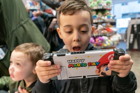 In this photo provided by Nintendo of America, Luke T., 6, and Jack T., 3, celebrate Mario Day (MAR10) at the Nintendo NY store in Rockefeller Plaza by personalizing their Nintendo Switch system with a special MAR10 Day-themed skin made by Controller Gear. (Photo: Business Wire)