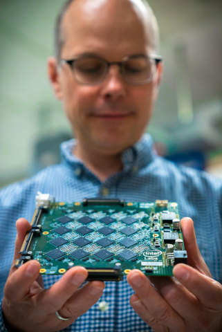 Rich Uhlig, managing director of Intel Labs, holds one of Intel’s Nahuku boards, each of which contains 8 to 32 Intel Loihi neuromorphic chips. Intel’s latest neuromorphic system, Pohoiki Beach, is made up of multiple Nahuku boards and contains 64 Loihi chips. Pohoiki Beach was introduced in July 2019. (Credit: Tim Herman/Intel Corporation)