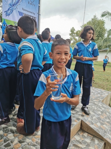 A child from the Sa Kaeo province in Thailand enjoys a glass of water after Watts and Planet Water Foundation built a water filtration tower that provides 1,000 people with 10,000 liters of clean water per unit daily. (Photo: Business Wire)
