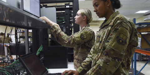 380th Expeditionary Communications Squadron client system technicians Senior Airman Ashley Yarbrough (middle) reimages a computer while Airman 1st Class Angela George (right) installs and updates software on a computer, Nov. 28, 2018 at Al Dhafra Air Base, United Arab Emirates. If a portion of the base loses any capability, the Comm squadron has to perform maintenance on potentially several fronts spanning local and remote locations. (U.S. Air Force photo by Tech. Sgt. Darnell T. Cannady) Photo courtesy of Defense Visual Information Distribution Service (DVIDS).