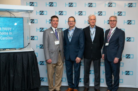 HZO and Government Leaders at the Open House, pictured next to a fully submerged LED display, protected by HZO's waterproofing technology . From Left: TJ Cawley, Mayor of Morrisville, North Carolina, Stephen Gold, HZO Chief Commercial Officer, Bill McCombe, HZO Chief Financial Officer, and John Hardin, Executive Director of the Office of Science, Technology & Innovation in the North Carolina Department of Commerce (Photo: Business Wire)