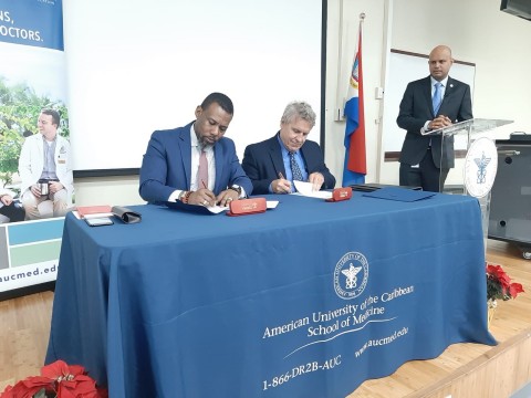 Ronald Jackson, CDEMA Executive Director and Dr. Mark Quirk, Executive Director of the Caribbean Center for Disaster Medicine and Senior Associate Dean for Medical Education at AUC School of Medicine, sign an agreement to increase collaboration while Hazarie Ramoutar, Senior Administrator for Campus Operations at AUC School of Medicine, looks on. (Photo: Business Wire)