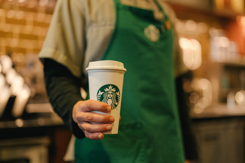 A Starbucks barista hands a reusable cup to a customer. As part of the company’s new sustainability commitments, the company is working to encourage more use of reusable cups. (Photo: Business Wire)
