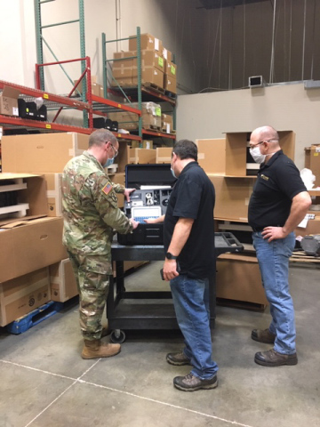 Captain Adam Hever of Army National Guard Bureau (NGB) Headquarters, Savi Technology’s Doug Schreffler and Chris Macek of First Source Electronics (FSE), a division of Commercial Vehicle Group, Inc., inspect order of 221 Savi Portable Deployment Kit (PDK) III units at FSE's Maryland location. (Photo: Business Wire)