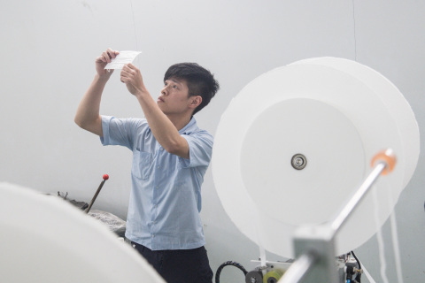 On April 30, a technician in Wugu District, New Taipei City, inspects a sample at Chang Hong Machinery, one of several local manufacturers that form Taiwan’s “national team” responsible for building production lines and increasing the country’s mask output to 20 million pieces per day. (By Lin Chun-yao, CNA)