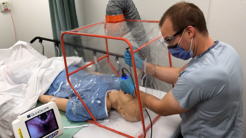 Dr. Marc Curial demonstrates use of the portable Aerosol Containment Tent (ACT) on a mannequin. (Photo: Business Wire)