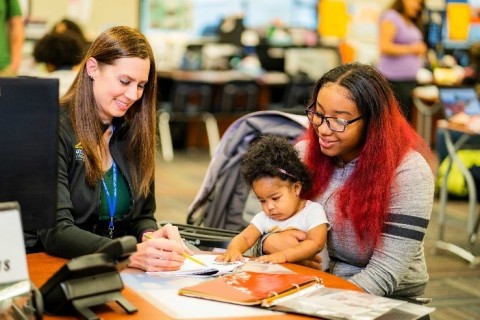 A Learn4Life student interacts with her supervising teacher while holding her baby. (Photo: Business Wire)