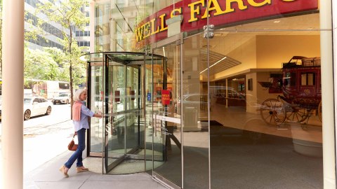 Woman entering a Wells Fargo branch with a glass front through a revolving door. (Photo: Wells Fargo)
