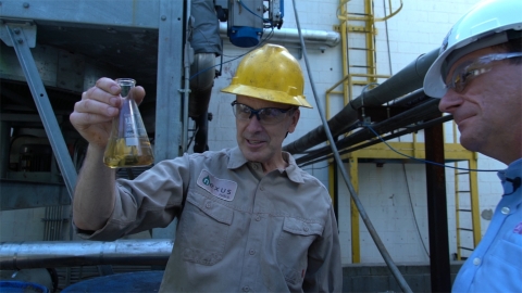 Jeff Gold of Nexus Fuels holds a beaker of recycled liquid from  Yamaha shipping plastic that can be repurposed into other materials. (Photo: Business Wire)