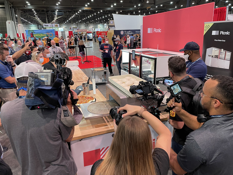 Pizza Expo attendees eagerly watch the Picnic Pizza System make the perfect pizza and recognize how the system saves time, money, and labor. Pricing ranges from $3,500 to $5,000 per month including free installation and maintenance. (Photo: Business Wire)