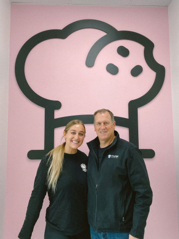 Pictured at their flagship store in Marysville, Washington: Crumbl Cookies Franchise Owners Kylie McDonald and her father, Matt McDonald. (Photo: Business Wire)
