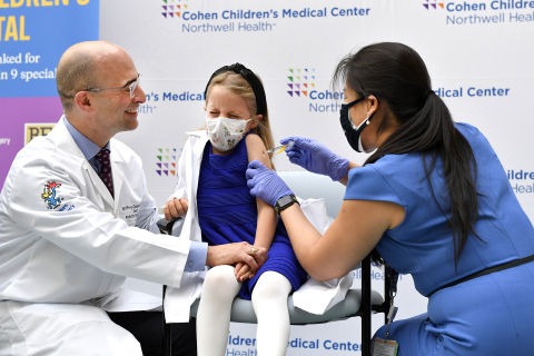 Northwell Health’s Jeff Gossett, MD, comforts his 7-year-old daughter, Nora, as Sophia Jan, MD, administers the first child dose of Pfizer-BioNTech COVID-19 vaccine at Cohen Children Medical Center. Credit Northwell Health.