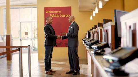 Wells Fargo employee shaking hands with customer in front of the teller line. (Photo: Wells Fargo)