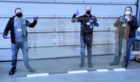 Image of Ubiquitous Energy team holding 1.5 x 3.0 meter size glass coated with one of Ubiquitous Energy’s UE Power™ transparent solar materials (Photo: Business Wire)