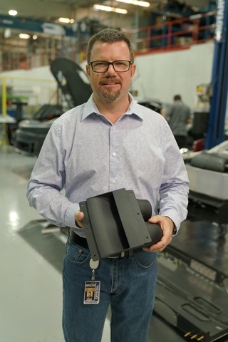 NASCAR Next Gen car designer holding the 3D printed windshield air cockpit ventilation unit. (Photo: Business Wire)