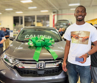 Recipient Jevonne Wilson Browne smiles for the camera and in front of his newly refurbished vehicle thanks to National Auto Body Council's Recycled Rides® program and partners Caliber Collision and USAA. (Photo: Business Wire)