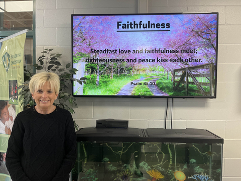 original Deb Poggensee in front of the digital signage at Pickering Christian School. (Photo: Business Wire)