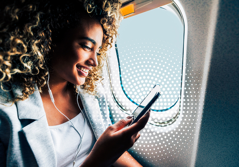 Woman enjoying seamless connectivity on her mobile device during her flight. (Photo: Business Wire)