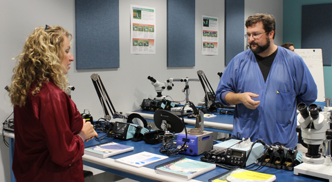 Kathy Leggett, Future Ready Iowa policy advisor, talks with Nick Turnis, Crystal Group production quality lead and IPC trainer, about the new soldering lab training program the company implemented this year with a grant from the Employer Innovation Fund. (Photo: Business Wire)