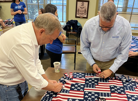 Corvias CEO Chris Wilson and Michael Paz-Torres, Regulatory Compliance Specialist, assemble blankets that will be donated to a unit at Fort Riley that will soon deploy. (Photo: Business Wire)