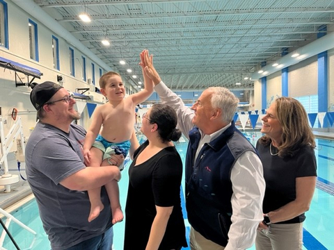 Steve Rosenthal, who recently made his second $1 million gift to the Northeast Arc, gets a high five from J.J. Millard, of Peabody, Massachusetts while visiting the Greater Beverly YMCA to see the organization’s Water Wise program in action. This is one of the many programs that was funded through Rosenthal's original gift. Pictured from left: J.J.’s father John Millard, J.J., his mother Joanna Millard, Rosenthal and Jo Ann Simons, President & CEO Northeast Arc. (Photo: Business Wire)