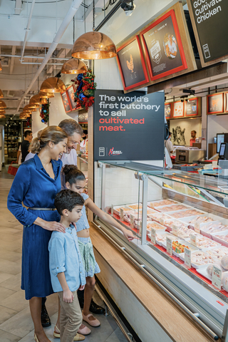A family looks at GOOD Meat's cultivated chicken in the display case at Huber's Butchery (Photo: Eat Just, Inc.)