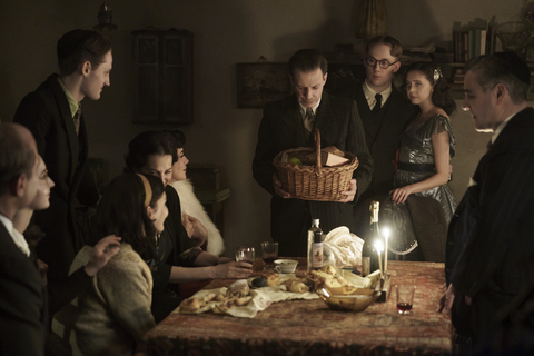 The Frank, van Pels and Gies families celebrate Hanukkah in the upcoming limited series A SMALL LIGHT, from National Geographic and ABC Signature in partnership with Keshet Studios. From left: Liev Schreiber as Otto Frank, Ashley Brooke as Margot Frank, Rudi Goodman as Peter van Pels, Billie Boullet as Anne Frank, Amira Casar as Edith Frank, Caroline Catz as Mrs. van Pels, Noah Taylor as Dr. Pfeffer, Joe Cole as Jan Gies, Bel Powley as Miep Gies, and Andy Nyman as Mr. van Pels. (Photo credit: National Geographic for Disney/Dusan Martincek)