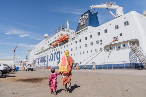 Amadou, the first patient to receive surgery on the Global Mercy®, approaches the ship with his caregiver, Mariatou. (Photo: Business Wire)