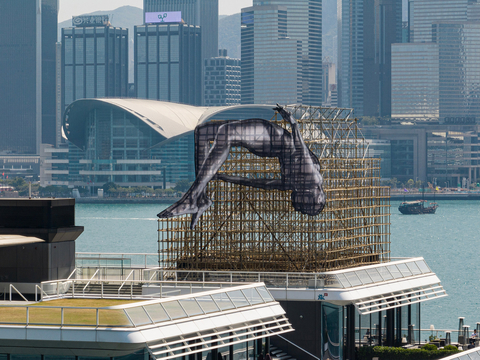 Harbour City the current home of "GIANTS: Rising Up." This is the first of French artist JR's "GIANTS" series in Asia. The 1200 sq ft. installation depicts a high jumper gracefully backdropped against the iconic Victoria Harbour and features a nod to traditional Hong Kong craftsmanship with the use of bamboo scaffolding. The installation will be on display through April 23, 2023. (Photo: Business Wire)