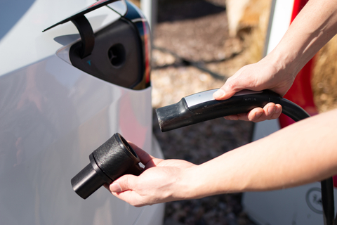 Electric vehicle driver attaches the EVject safety adapter to a Tesla charging head. (Photo: Business Wire)