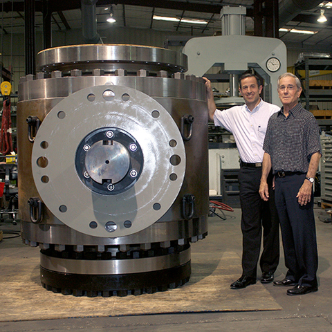 Matt Mogas (left) and Louis Mogas (right) pose next to a large MOGAS ball valve (Photo: Business Wire)