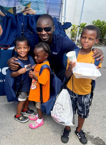 Senior Manager of Logistics Jide Dawodu shares a moment with children at the Backpack Drive Event. (Photo: Business Wire)