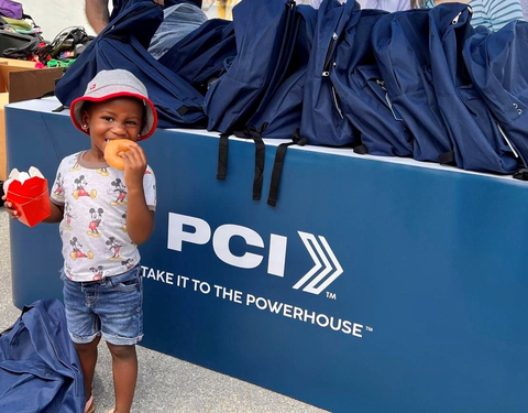 After receiving her school supplies, this little girl couldn't wait to get her fingers on one of the Krispy Kreme donuts provided by PCI at the event. (Photo: Business Wire)