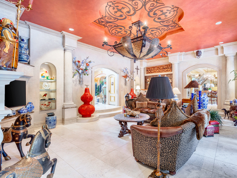 Shown here: the property's living room, decorated with various finds and treasures from the sellers' many world travels. Floors and built-ins are limestone. A custom iron chandelier with matching relief illuminates the room. NewYorkLuxuryAuction.com.