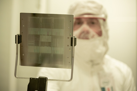 A member of the Intel Mask Operation team in Hillsboro, Oregon, holds a mask used in advanced lithography tools to create computer chips. The mask is created with a multimillion-dollar machine called a multi-beam mask writer built by the Austria-based company IMS Nanofabrication, an Intel company. (Credit: Intel Corporation)