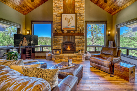 The main residence's living room exemplifies a style of relaxed, "rustic mountain luxury." Oversized windows surround the stone fireplace, filling interiors with natural light while offering endless views of the great outdoors. More at COLuxuryAuction.com. (Photo: Business Wire)