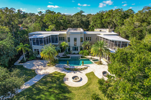 The rear, waterside of the property features a resort-style pool and spa, oversized pool deck, firepit lounge, and paved walkways to the boat dock. There are also screened outdoor living areas on the home’s upper and lower levels. WaterfrontLuxuryAuction.com. (Photo: Business Wire)