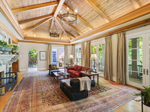 A welcoming living room features lofted ceilings with exposed wood beams, a wood-burning fireplace (at left) and a series of French doors opening to a loggia. NashvilleLuxuryAuction.com. (Photo: Business Wire)