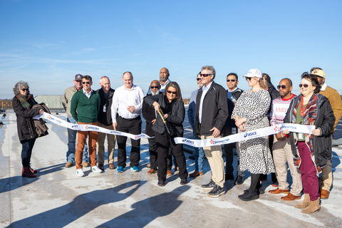 ASICS and PowerFlex team members cut co-branded ASICS and PowerFlex ribbon on top of roof with solar project in the background. (Photo: Business Wire)