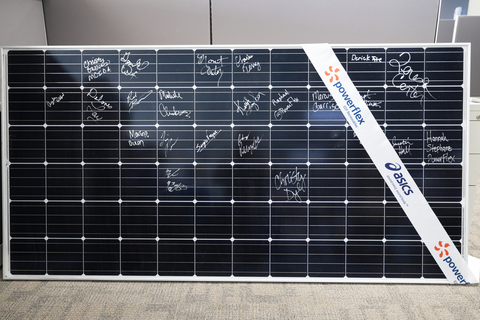 A solar panel with signatures and a co-branded PowerFlex and ASICS ribbon draped across corner. (Photo: Business Wire)