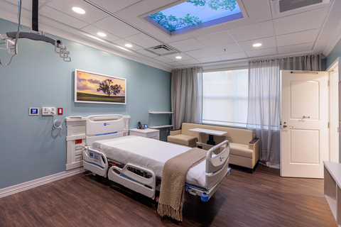 One of the 8 spacious and home-like patient rooms at the First Commerce Center for Compassionate Care featuring comfortable bed, sleeper sofa, and virtual skylight. The virtual skylight delivers multisensory and therapeutic illusions of beautiful real sky scenes through digital cinema. (Photo: Business Wire)