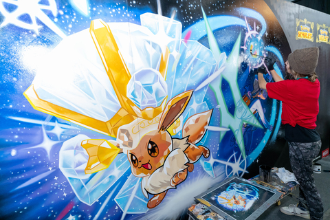 In this photo provided by Nintendo of America, an artist from Overall Murals adds finishing touches to a Pokémon Scarlet and Pokémon Violet themed mural at PAX East.