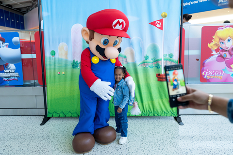In this photo provided by Nintendo of America, a young fan poses with Mario as she visits the “Nintendo Switch On the Go” popup in JetBlue’s Terminal 5 in John F. Kennedy International Airport in New York City.
