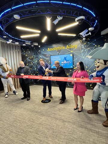 Axis Communications celebrated the grand opening of its latest Axis Experience Center (AEC) in Frisco, Texas on Wednesday, May 8, 2024, with a ribbon cutting featuring Dallas sports mascots and Axis management and staff: (L-R) Area Technical Manager Robert Drozd, Business Area Director Steve Stanberry, Senior Director of Sales Larry Newman, and Area Marketing Manager Lilian Marquez. (Photo: Business Wire)