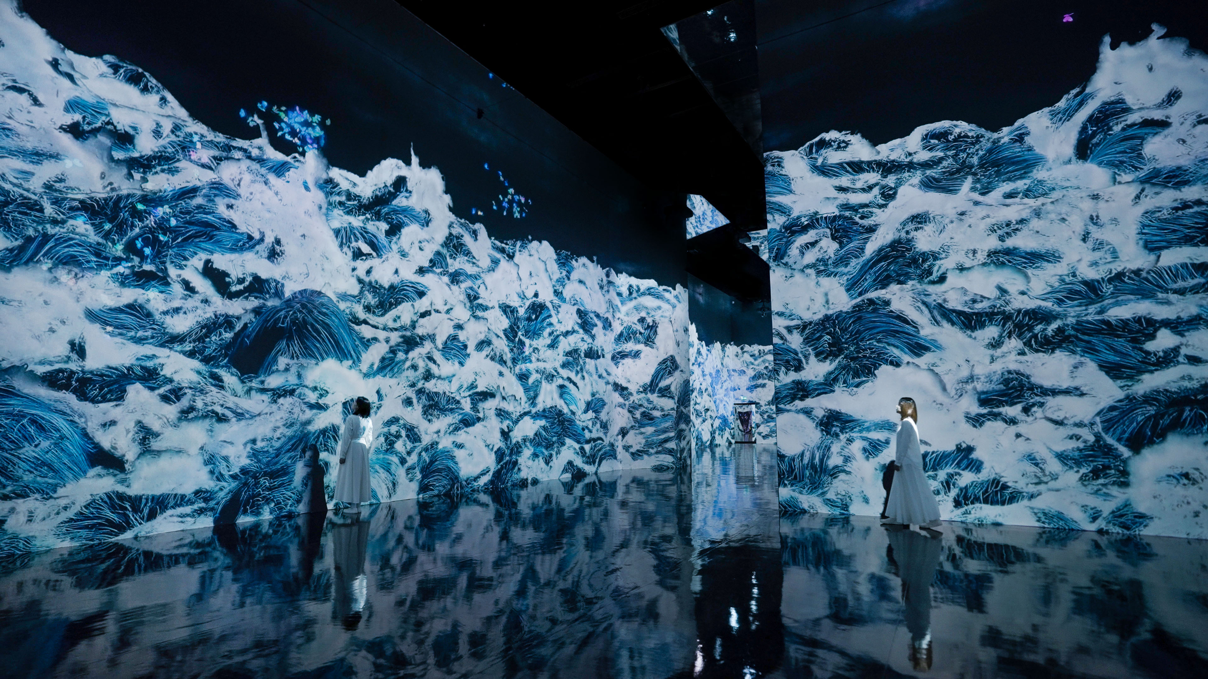 The artwork appears rising, filling the space. The work has no beginning or end, and is made up of one continuous wave that is all connected. The waves gradually shift, transcending boundaries and flowing into other rooms. On view at teamLab Borderless in Historic Jeddah. (teamLab, Black Waves: Flowing Beyond Borders / Video: teamLab)