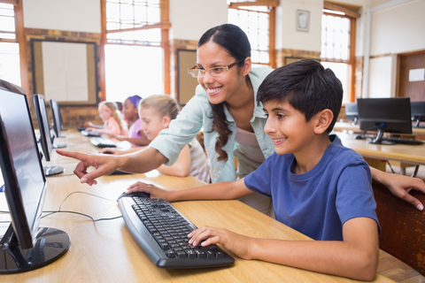 Teacher helps student on computer (Photo: Business Wire)