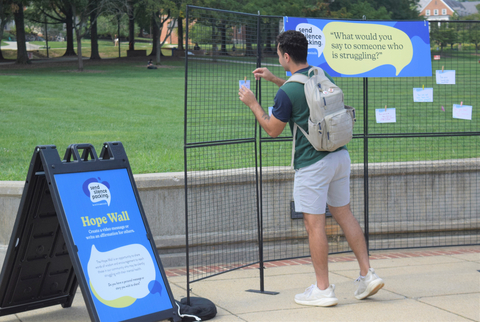 College student adding a personal message to the Hope Wall in the Send Silence Packing exhibit (Photo: Business Wire)