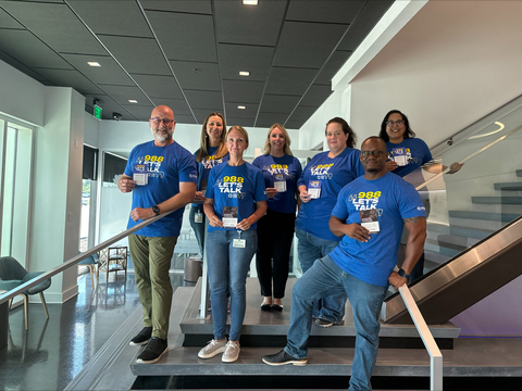 From left to right: MITER Brands team members: Bryan Lingle, Jennifer Meyer, Amy Lowery, Amie Brooks-Huff, Coley Pelletier, Ray Jones, and Veronica White wearing their “988 Let’s Talk” t-shirts and displaying information cards in honor of National Suicide Prevention Week (Photo: Business Wire)